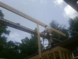 Carpenter setting a ridge beam over a new addition frame — Ice Dam Removal by Roofing Brothers in Chatom