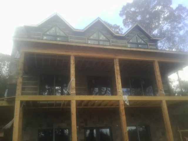 Dormers and porch framing on a large log home under construction — Roof Coating work by our crew in Chatom