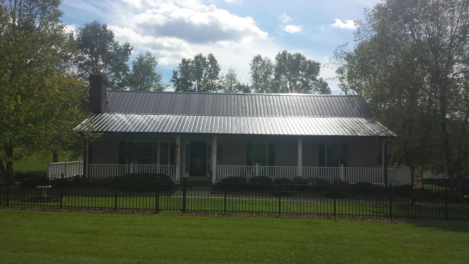 Gray metal roof on a brick ranch with a full width front porch — Gutter Guard Installation work by our crew in Chatom