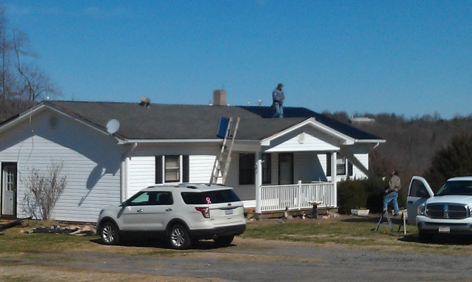 Roofers stripping shingles from a white ranch house roof in Chatom