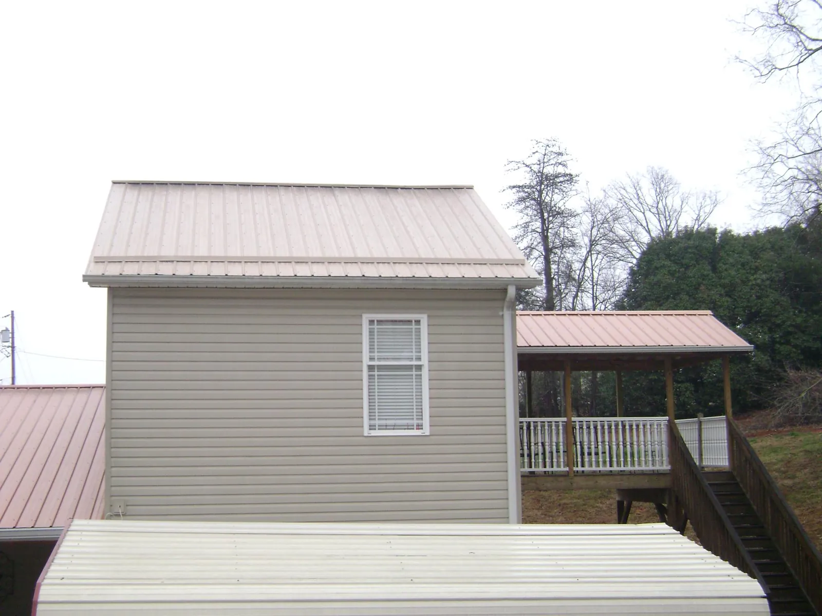 Tan metal roofs on a two story addition and attached porch, from a Roof Replacement job in Chatom