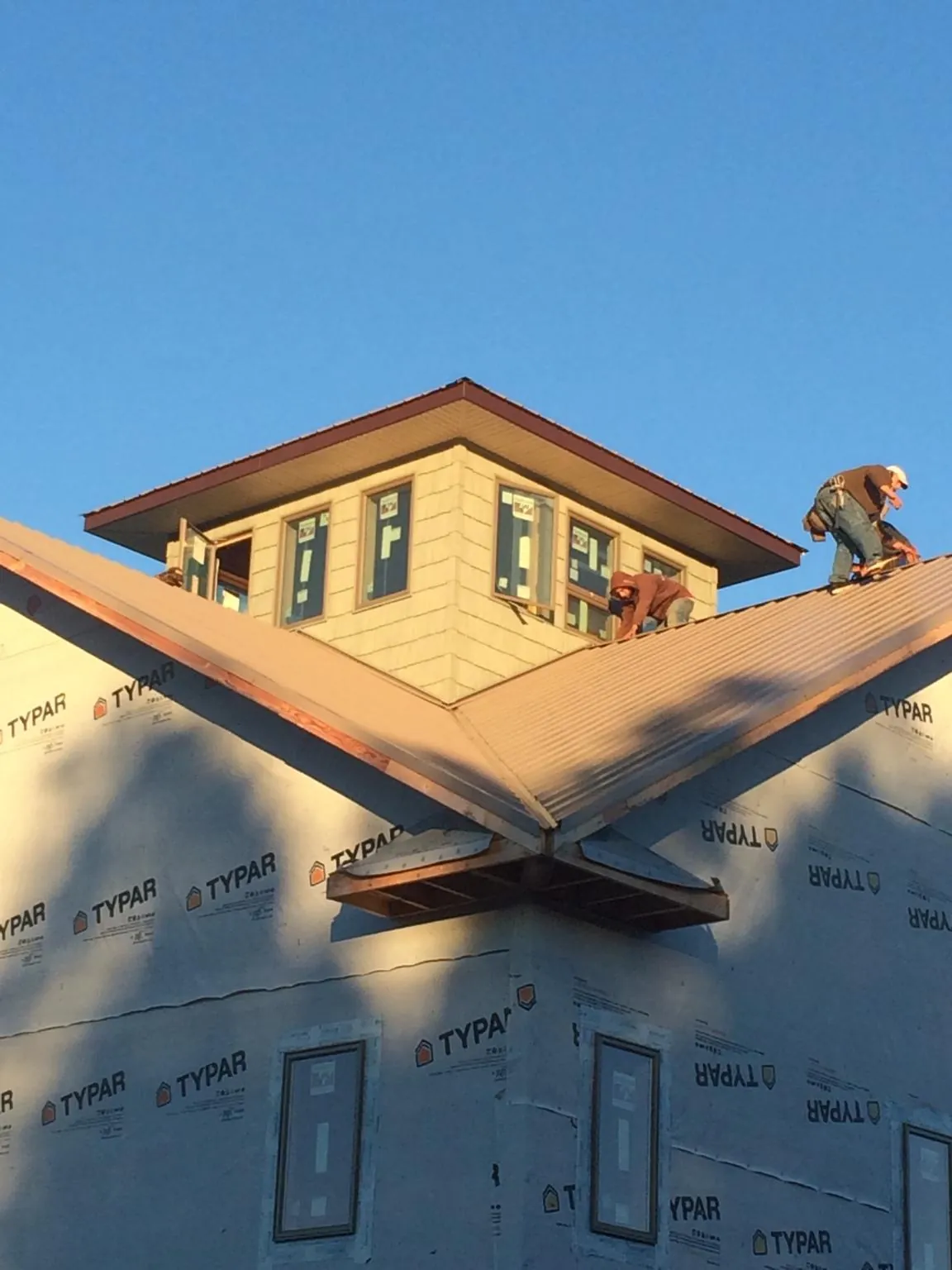 Roofers working around a rooftop cupola on a new metal roof at sunset — Roof Waterproofing in Chatom by Roofing Brothers
